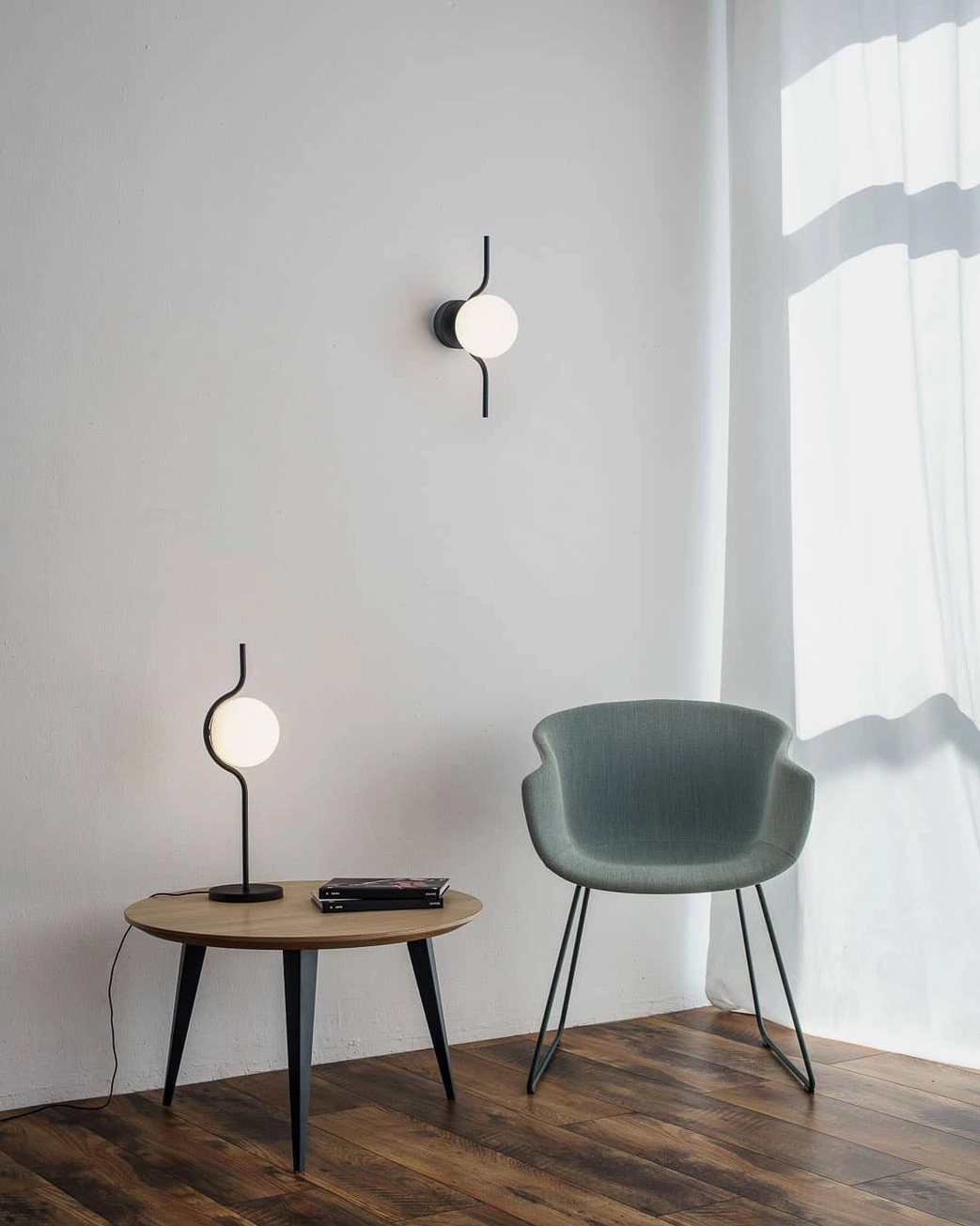 Levita black matte globe wall sconce paired with matching table lamp in cozy residential sitting area with wood flooring
