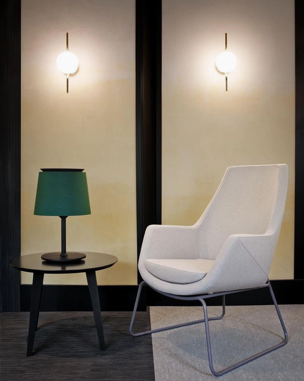 Two Levita globe wall sconces with white frosted glass installed in modern lounge corner with dark accent wall trim