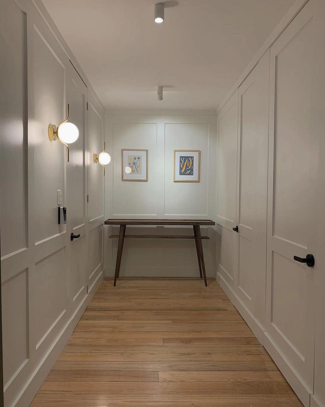 Pair of Levita frosted glass globe wall lamps illuminating residential hallway corridor with warm ambient lighting