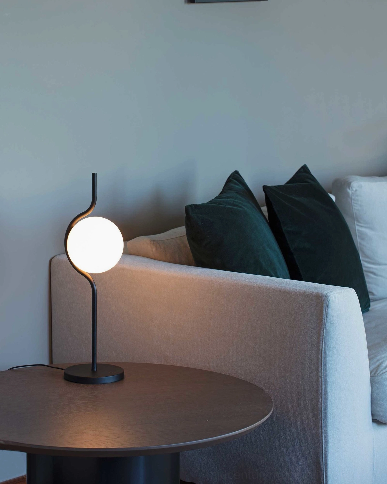 Slim straight stem Levita table lamp with black metal frame and spherical frosted glass shade in modern living room