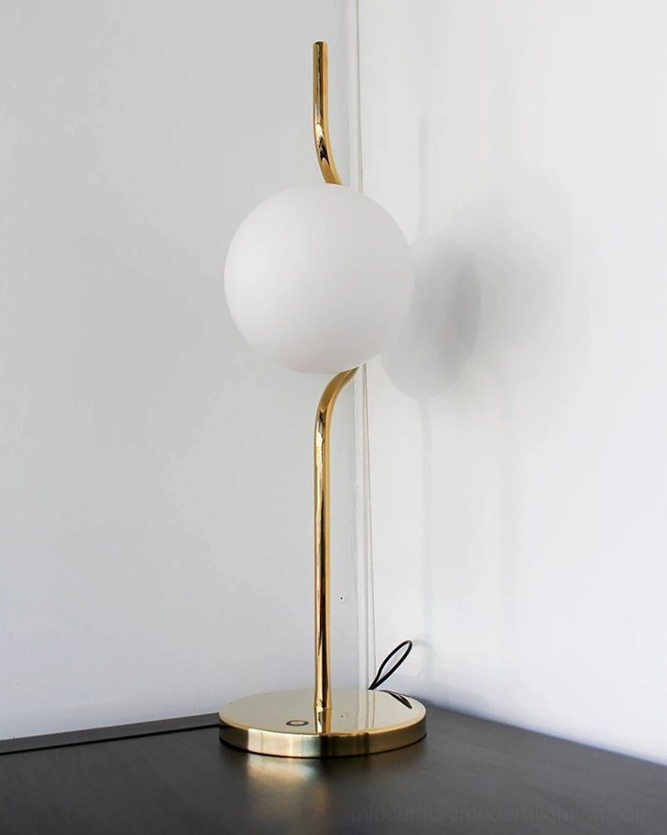 Sleek curved stem Levita table lamp with polished gold metal finish and frosted white glass sphere on side table