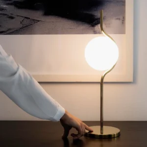 Levita table lamp illuminated warm light casting ambient glow on dark wood table surface with minimalist decor