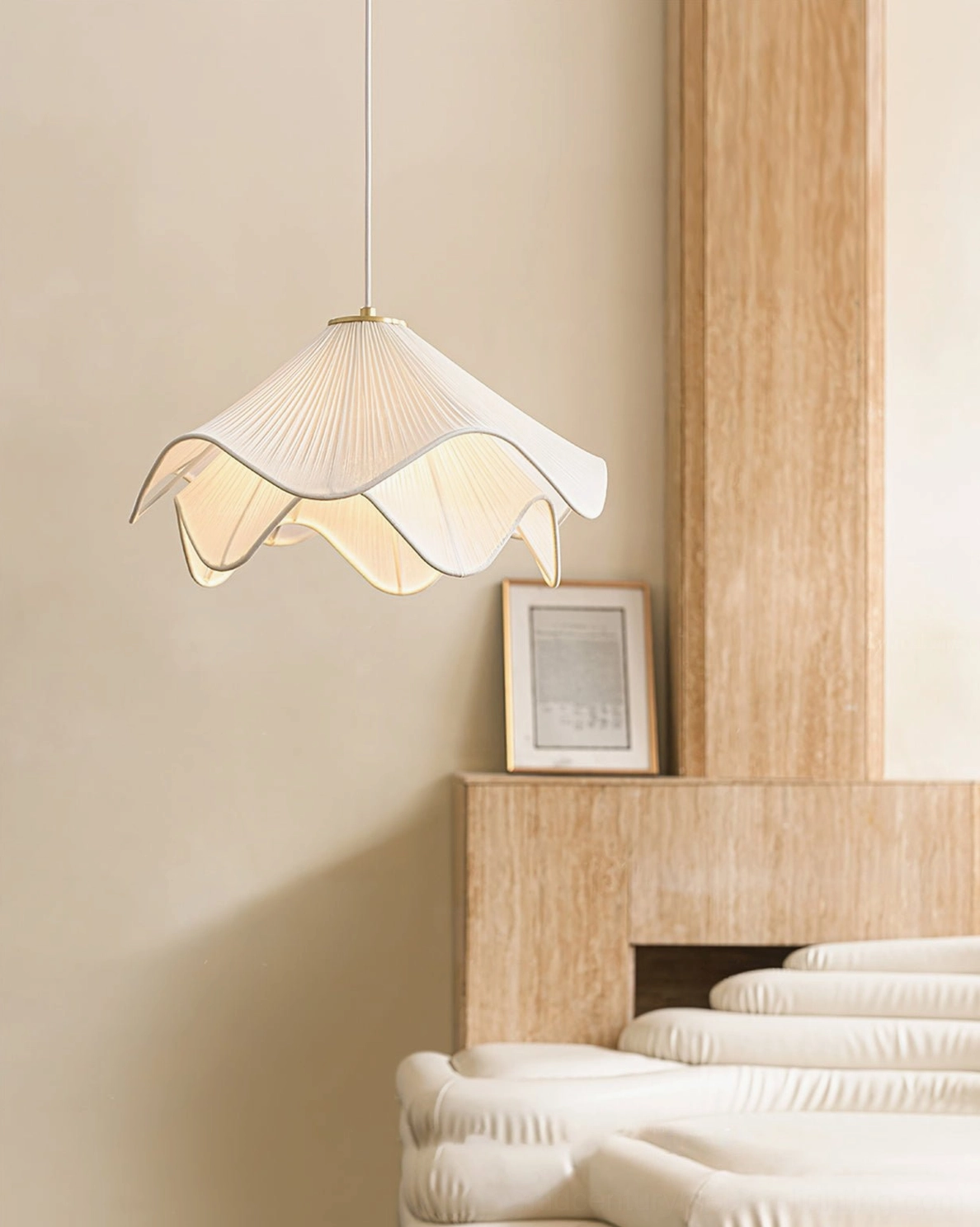 Low angle view of Lia pleated pendant fixture, showing brass top mount detail in warm bedroom with daybed and fireplace, modern hanging light design