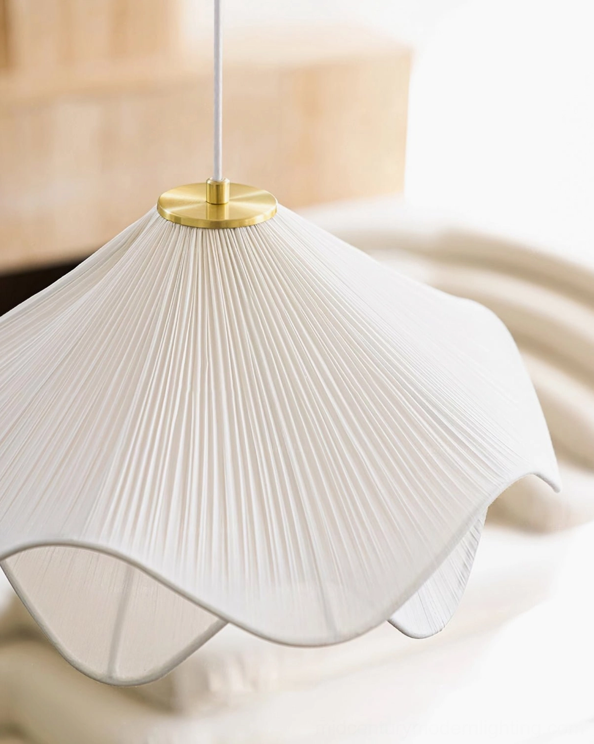 Close-up of Lia pleated fabric shade showing fine geometric pleating detail, brass suspension hardware, and soft textile texture