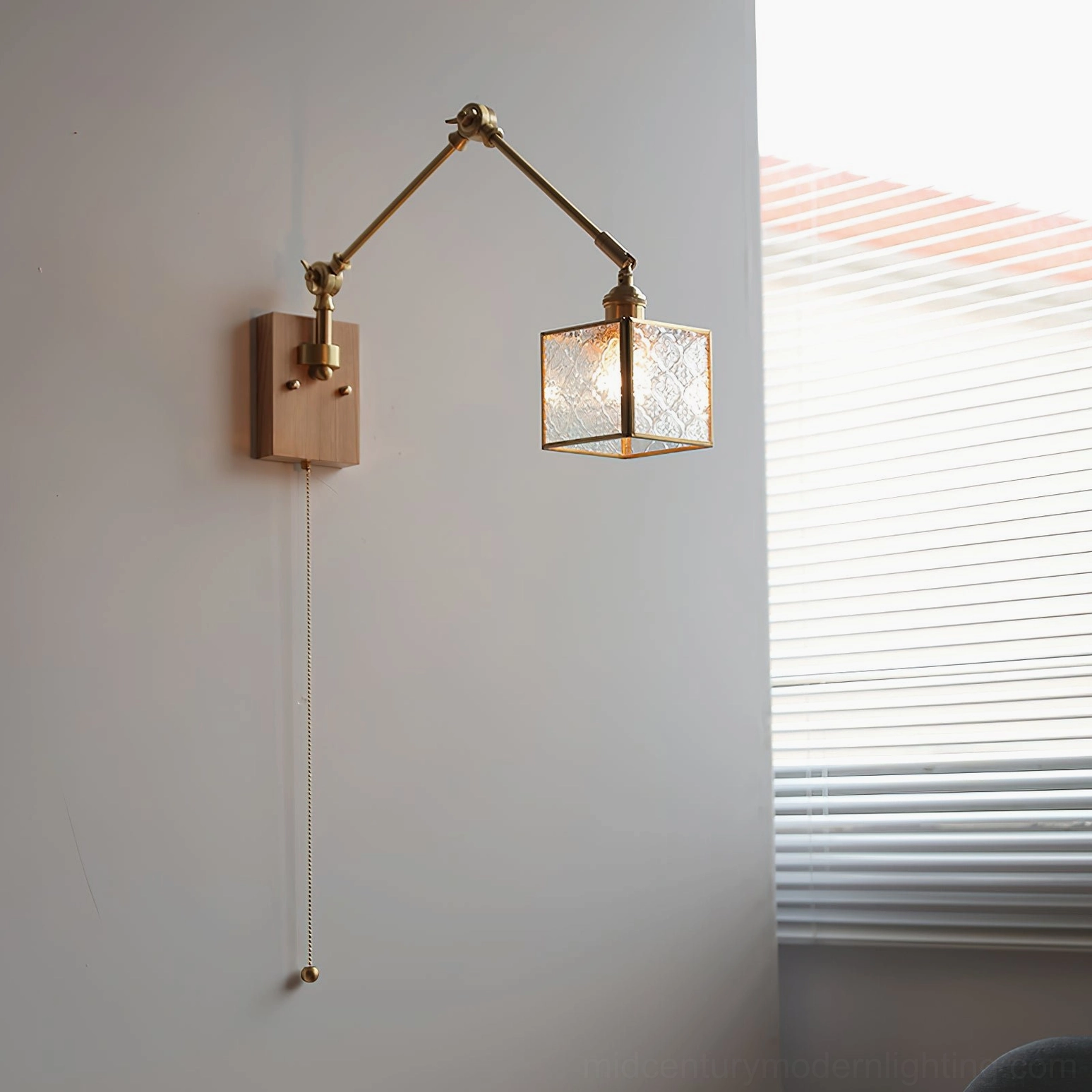 Light wood swing arm wall lamp with brass arm and ribbed glass shade installed in minimal modern interior space