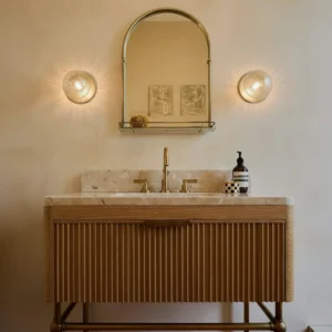Pair of Lila brass wall sconces installed above bathroom vanity mirror in minimalist modern setting