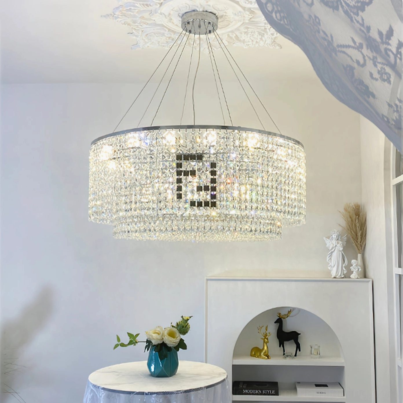 Two-tier crystal chandelier with silver suspension rods and layered geometric crystal design in minimalist home setting