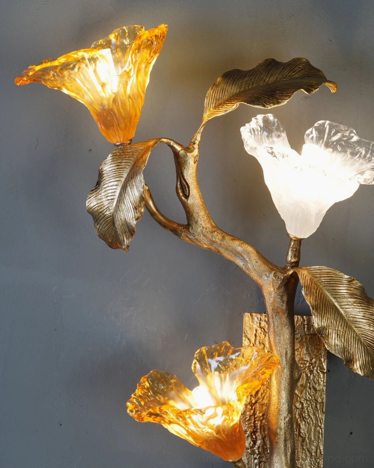 Lily branch brass wall sconce illuminated showing warm amber and frosted glass light diffusion