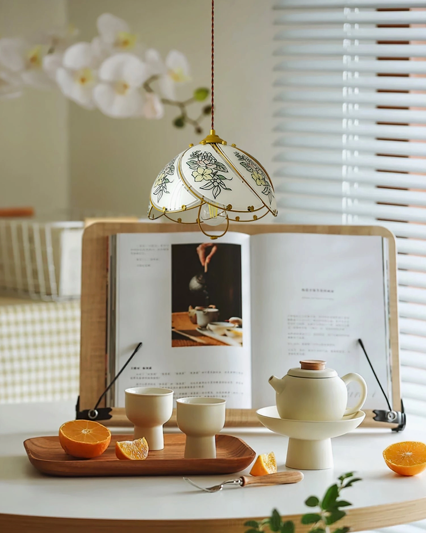 Floral pendant lamp illuminating cozy tea and reading corner with book and traditional window blinds, daily lifestyle setting