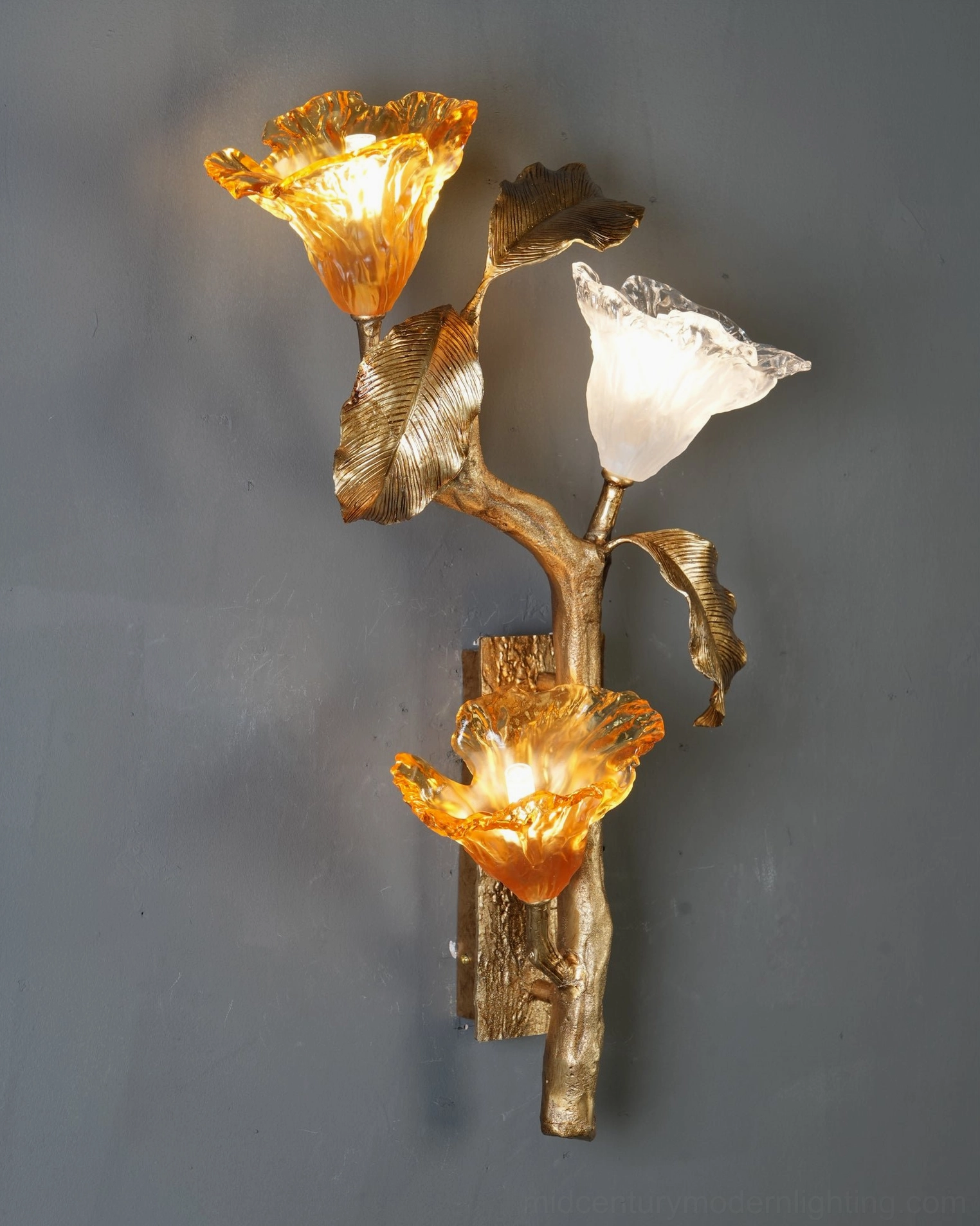 Close-up of hand-shaped glass lily blooms - two amber and one frosted glass with brass fixtures