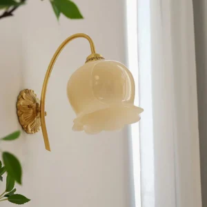 Mid-century modern lily of the valley wall sconce installed on bedroom wall with green plant decor