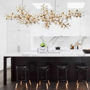 Linear grape vine chandelier suspended above modern kitchen island with warm brass finish and frosted white glass shades