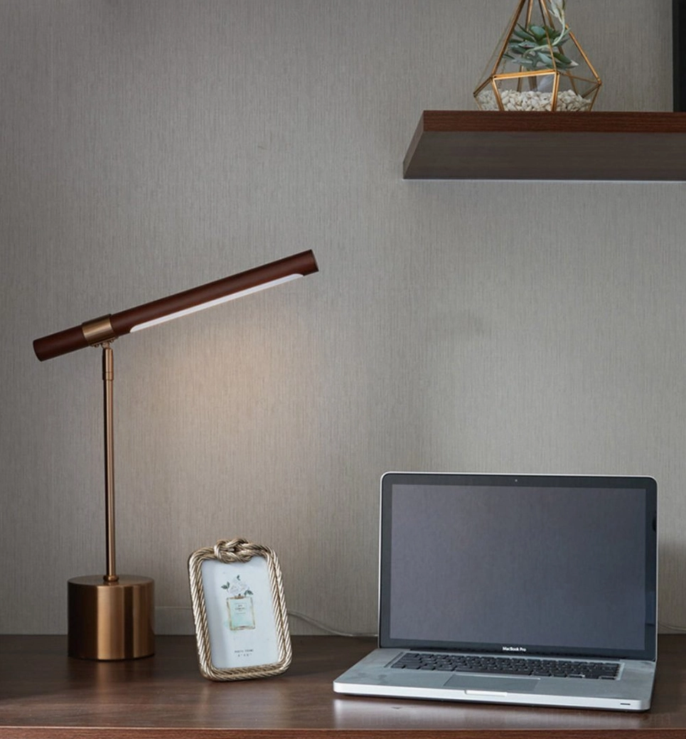 Gold metal desk lamp in contemporary office with laptop and vintage decor, wide room scene styling