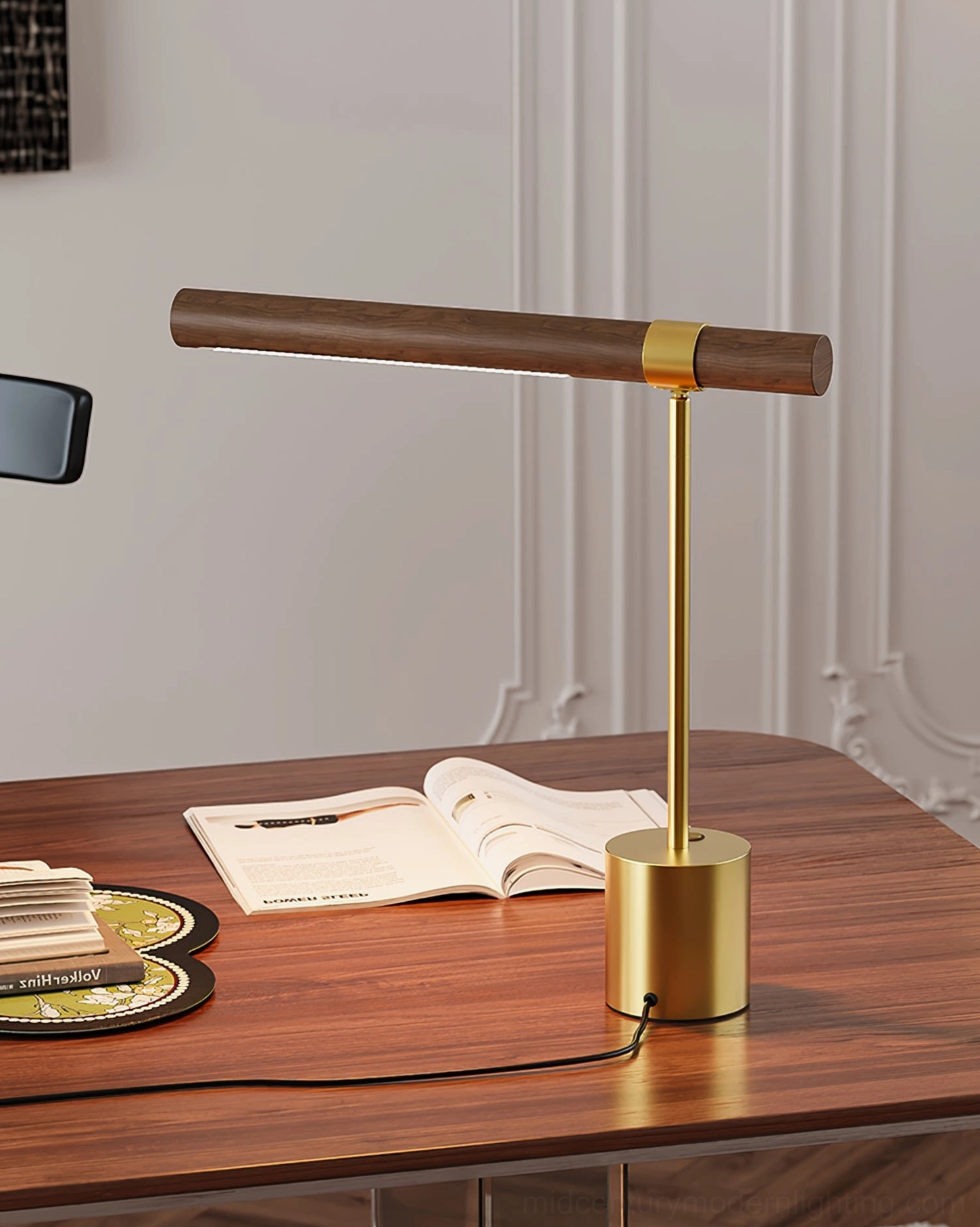Adjustable table lamp in home office workspace beside open book and wooden desk coasters, side-angle view