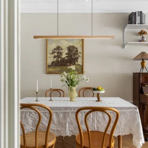 Modern linear wood chandelier suspended above dining table in rustic minimalist dining room with warm ambient lighting