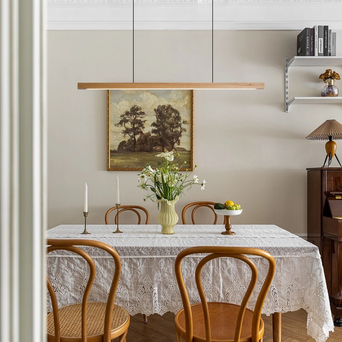 Modern linear wood chandelier suspended above dining table in rustic minimalist dining room with warm ambient lighting