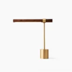 Linear adjustable table lamp with polished gold metal stem and walnut wood base, front view studio shot with minimalist styling