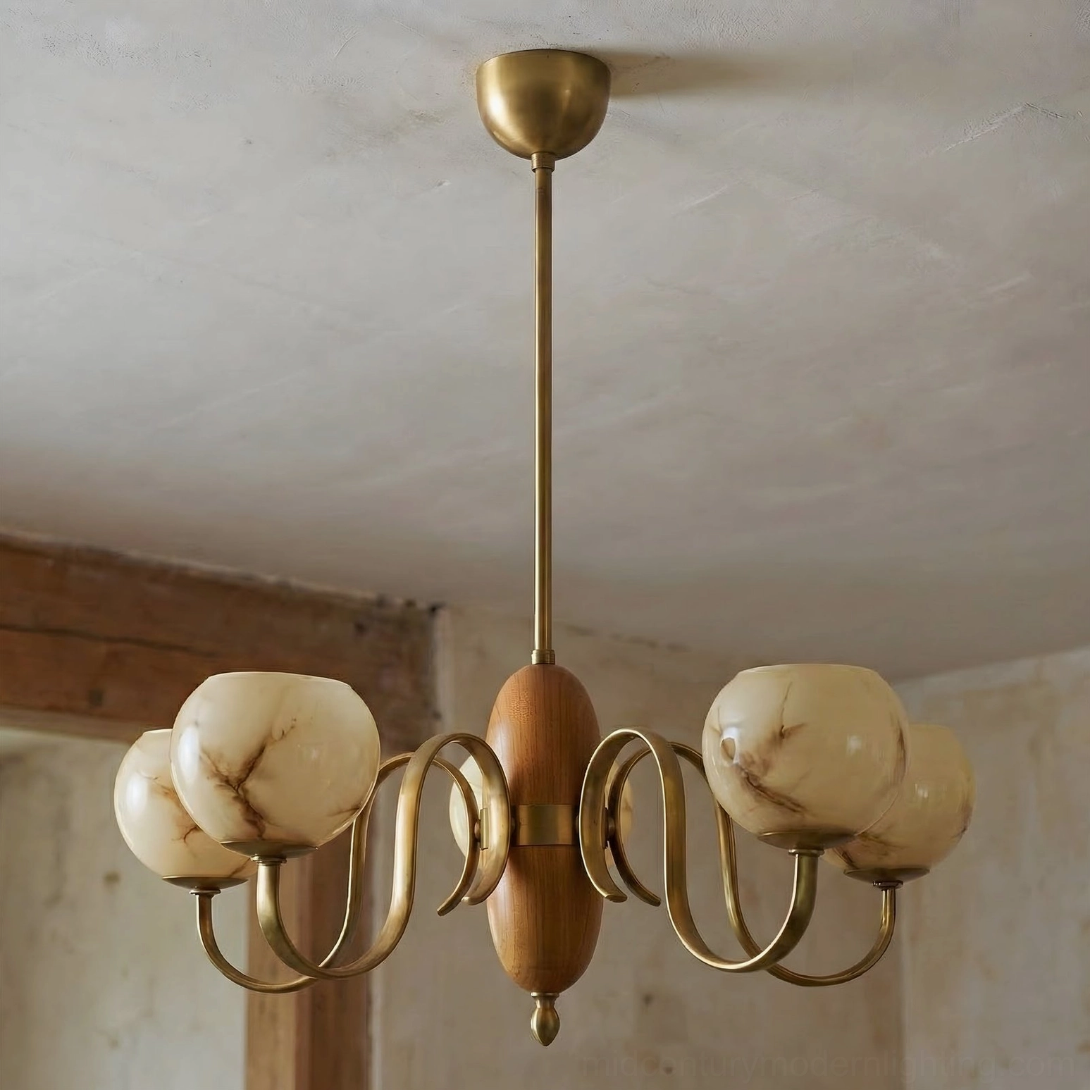 Linnea mid-century chandelier with veined cream glass shades and curved brass arms in rustic architectural setting
