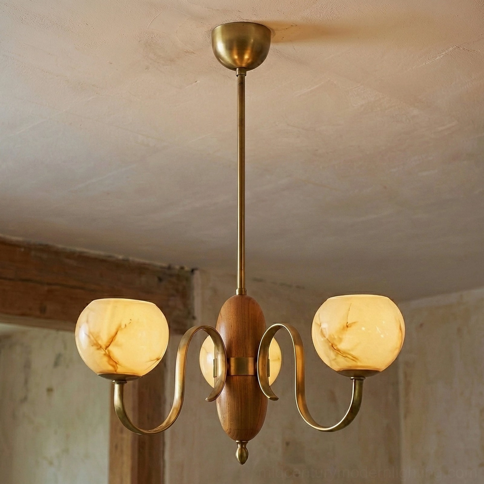 4-light Linnea mid-century chandelier with lit beige glass shades and curved brass arms in vintage rural interior