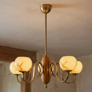 5-light Linnea chandelier illuminated in vintage interior space, showing warm honeyed glow from hand-blown glass shades