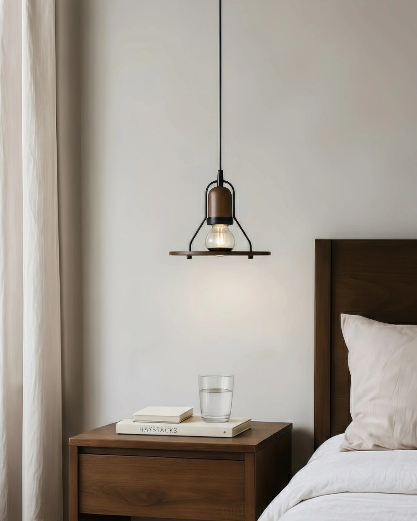 Industrial pendant light beside wooden nightstand in cozy bedroom, angled side view of hanging fixture
