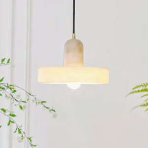 Lit alabaster pendant lamp illuminated with warm bulb in minimalist interior with green botanical decor