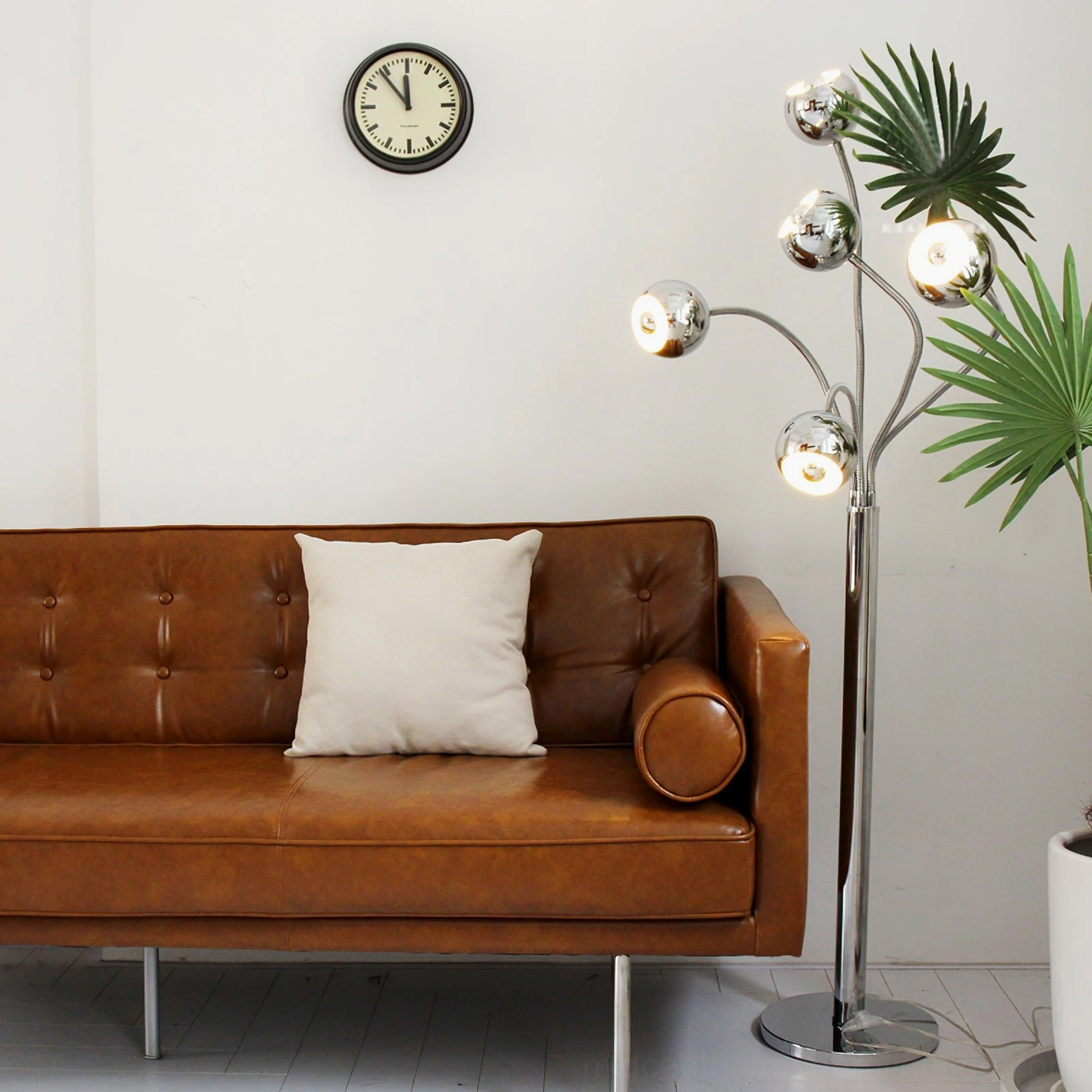 Illuminated chrome eyeball floor lamp with lit spherical heads in mid-century modern living room with brown leather sofa