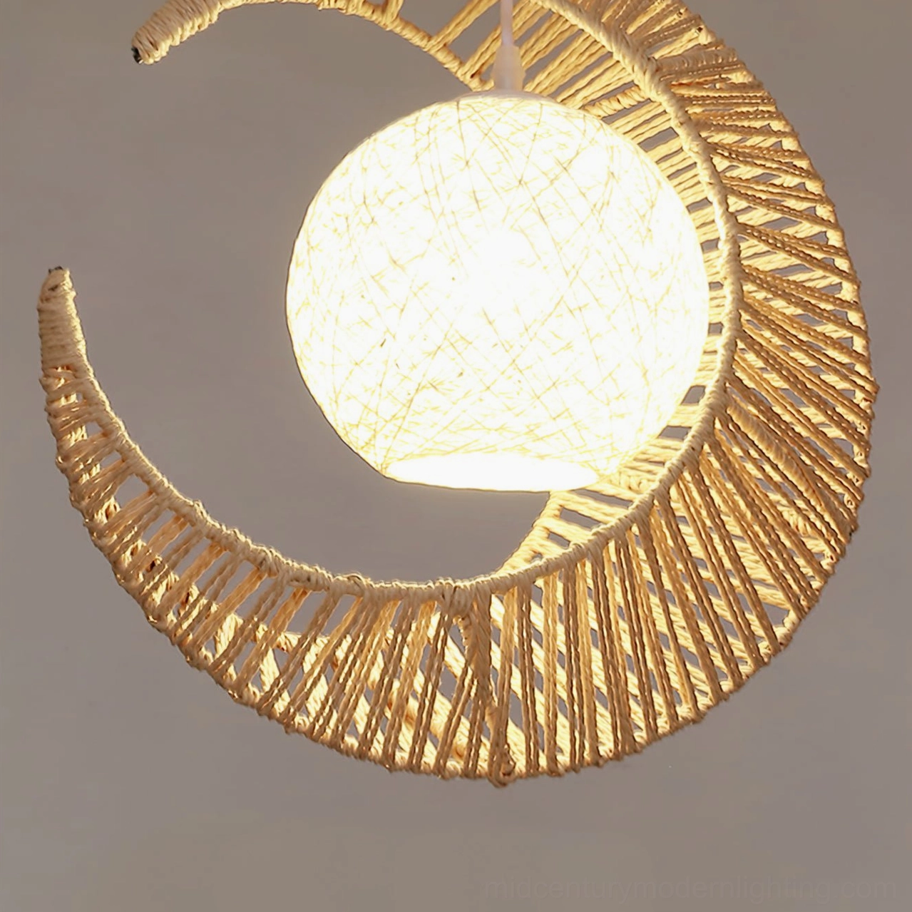Illuminated crescent moon pendant light with glowing spherical lampshade inside woven hemp frame