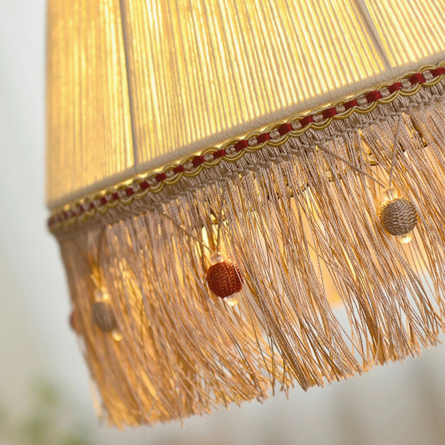 Lit beige fringe pendant lamp with warm glowing light and decorative tassel bead trim illuminated