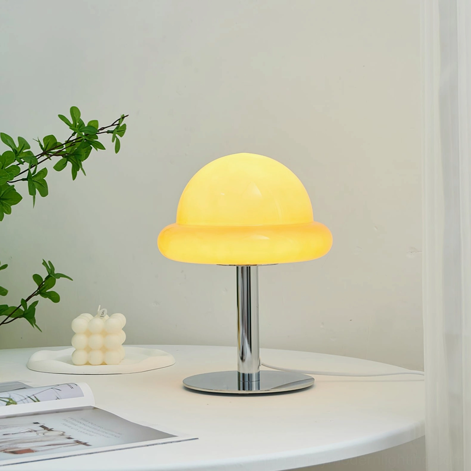 Illuminated orange retro mushroom table lamp glowing warm yellow light with polished chrome base on minimalist table