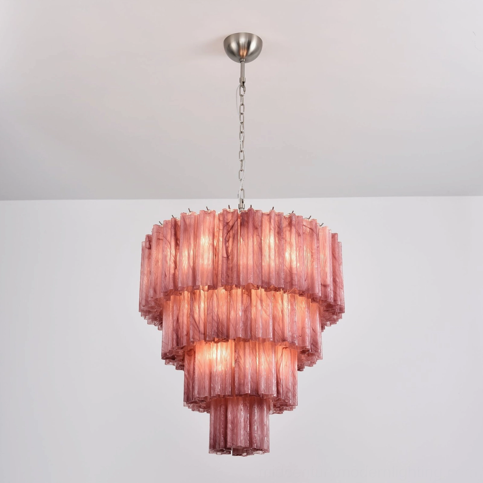 Lit dusty rose tiered glass chandelier overhead angle warm ambient lighting sculptural form