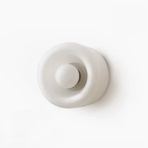 Lit round white glass wall lamp with warm ambient glow, beige wall with monstera leaf decor