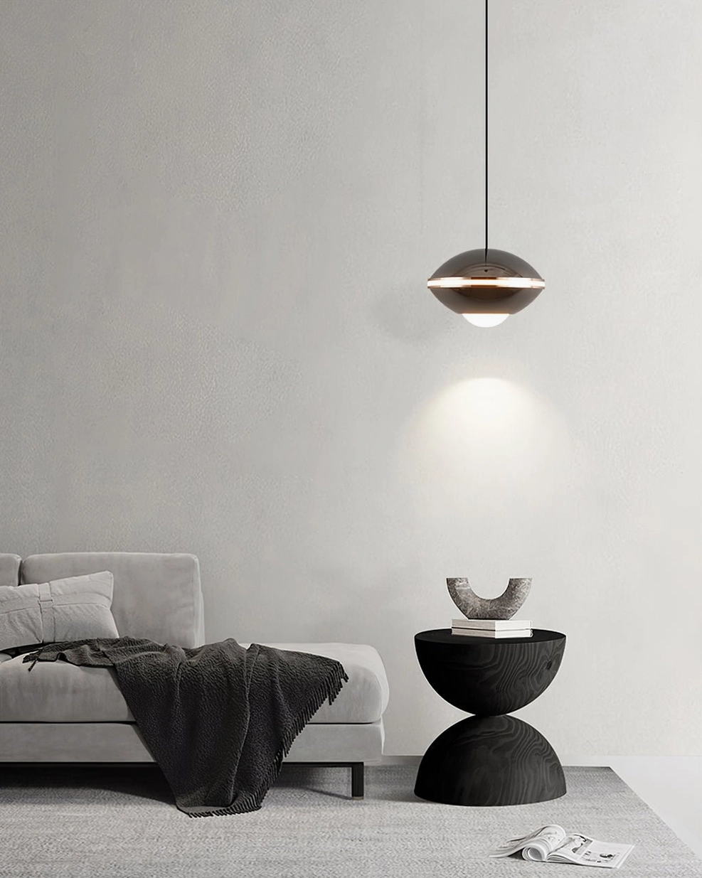 Minimalist saucer pendant lamp in living room nook, dark metal finish with warm wall-wash lighting