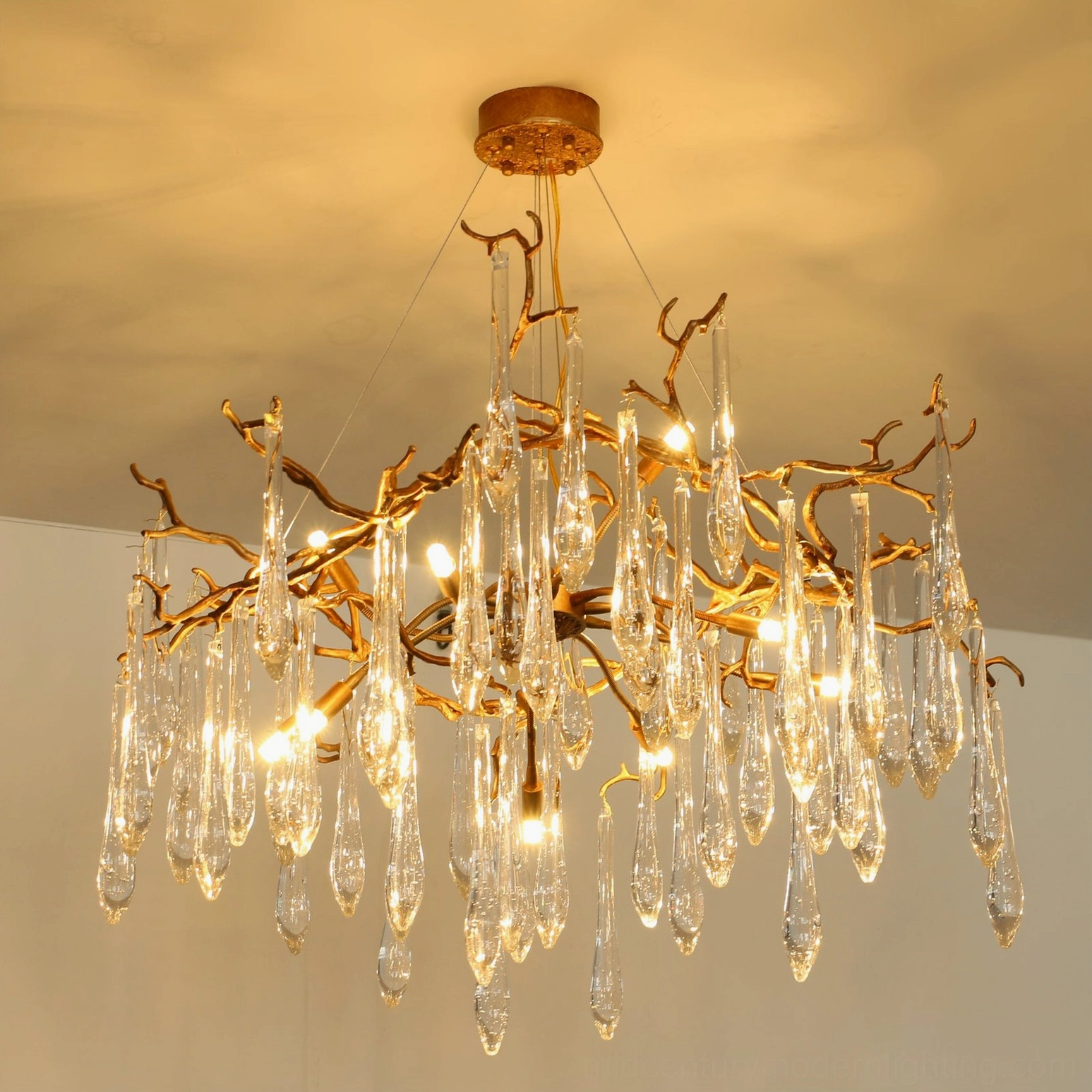 Medium Livio Chandelier (85cm) installed above dining table, demonstrating warm ambient lighting for entertaining