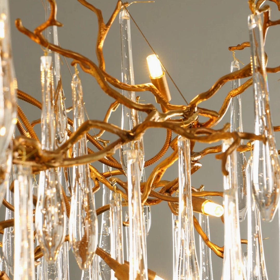 Side close-up of Livio Chandelier showing brass branches, teardrop crystals, and illuminated G9 LED bulbs