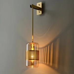 Lizak green glass wall lamp mounted on grey wall showing decorative shadow pattern cast by brass slats, close-up detail view
