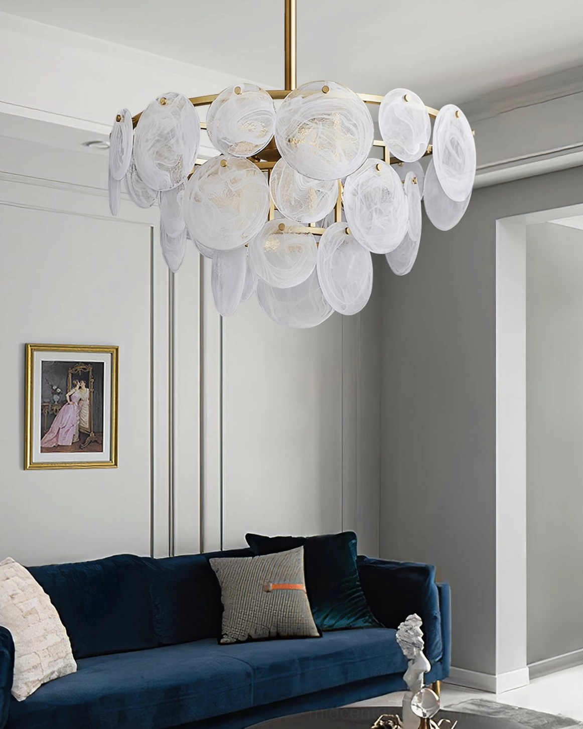 Loire Brass Chandelier above blue velvet sofa in cozy modern living room with framed wall art and soft panels