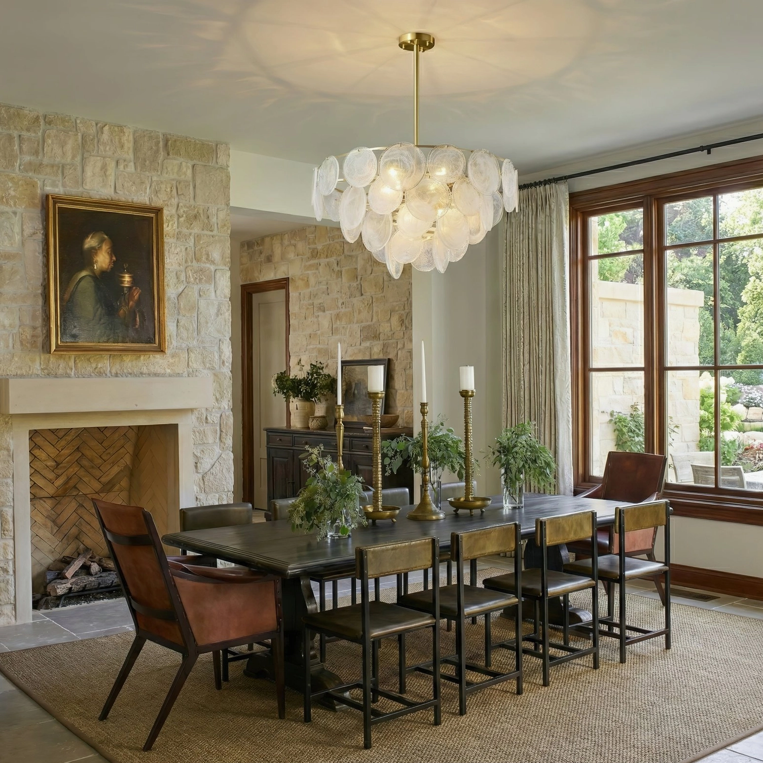 Loire Brass Chandelier installed in luxury dining room with stone fireplace and warm ambient lighting above dining table