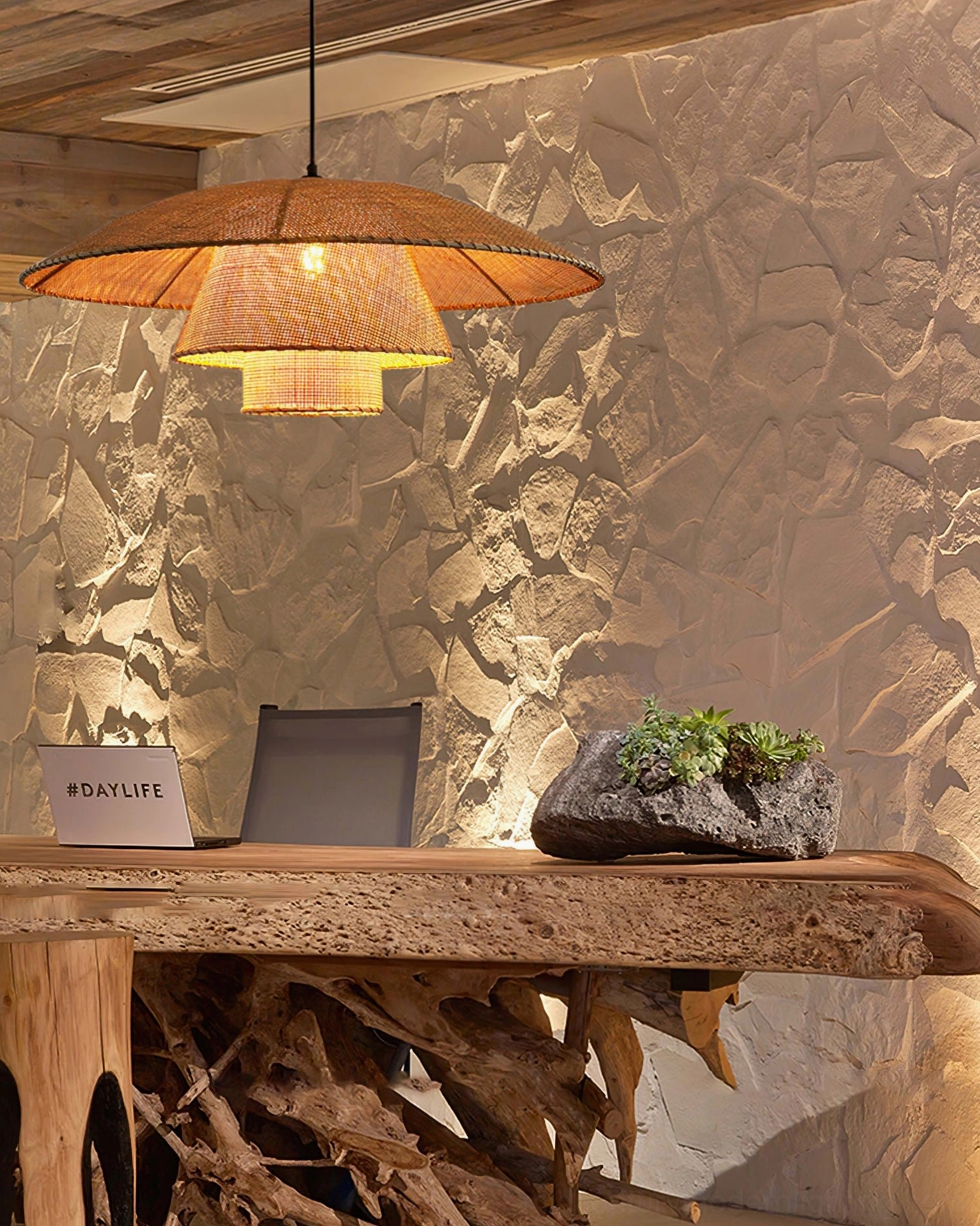 Layered rattan pendant lamp with dark brown finish in rustic wooden home office with stone accent wall