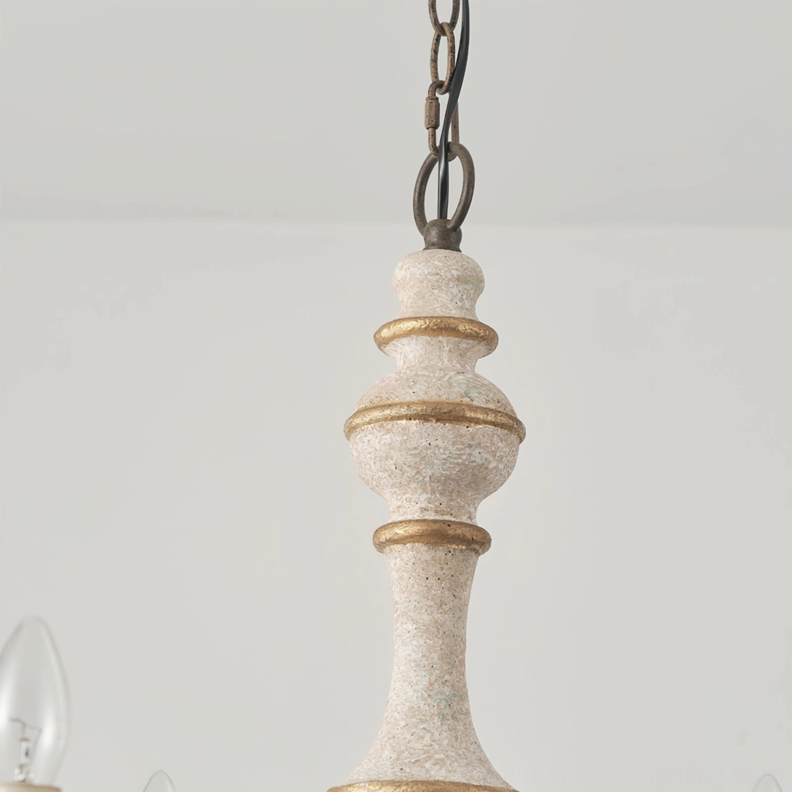 Lomba chandelier center post close-up showing aged white finish, gold decorative bands, and hand-crafted wooden details
