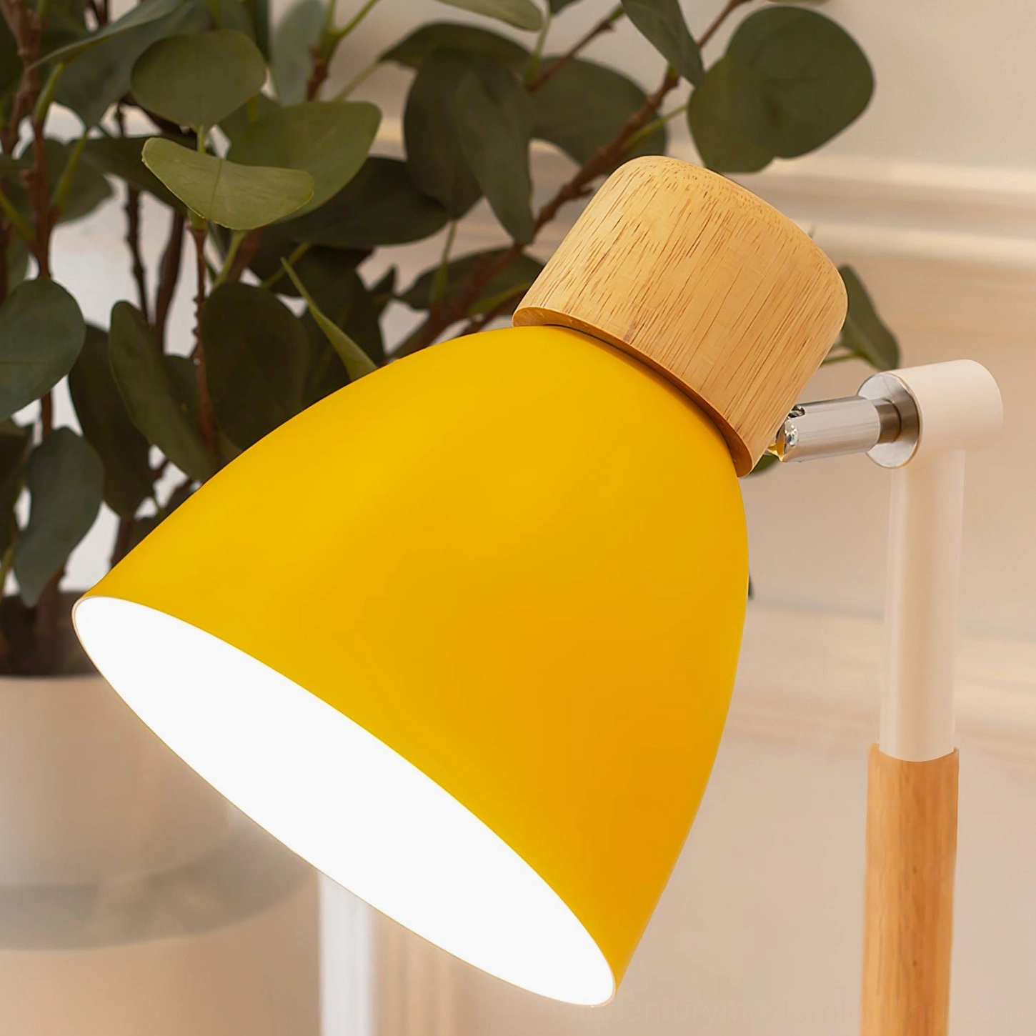 Close-up detail of Loona lamp showing adjustable metal hinge joint and matte yellow paint finish