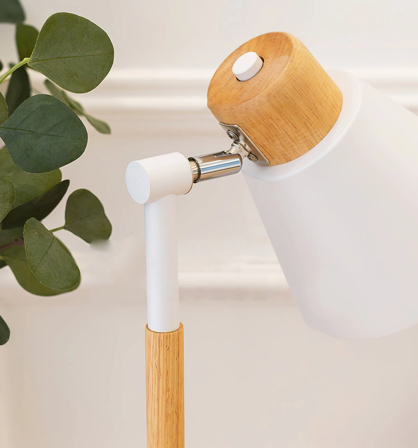 Rear view of Loona lamp showing wooden top cap, adjustable swing arm and control button with green plant background