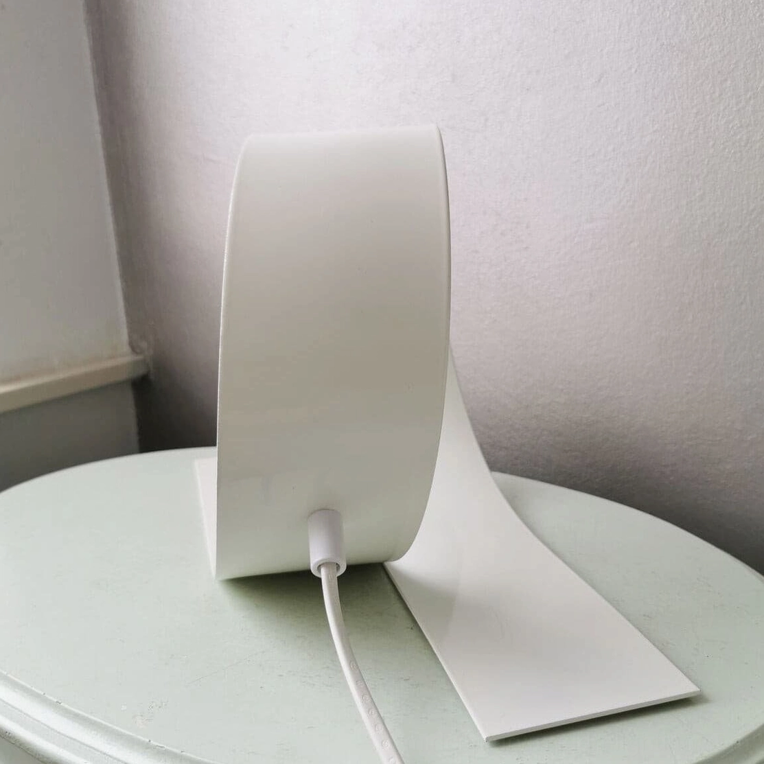 Sculptural white looping lamp with curved ribbon design on light green side table