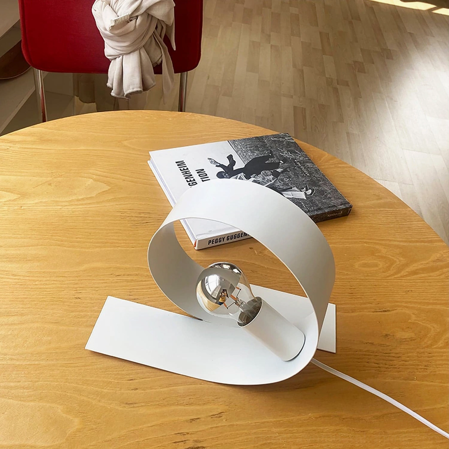 Geometric looping table lamp with circular loop design and exposed bulb on home dining table