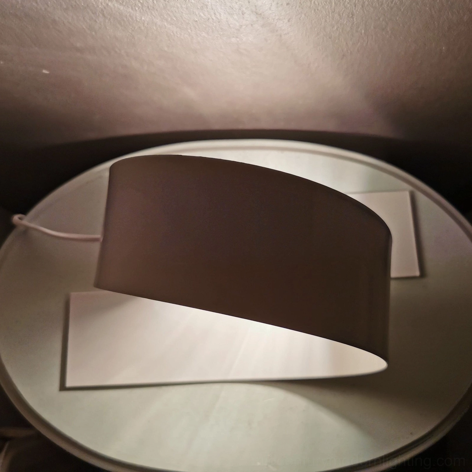 Looping table lamp overhead view with dark shade and white metal base on round side table