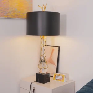 Lora table lamp three-quarter view in bedroom bedside setting with gold branch finial sculptural detail