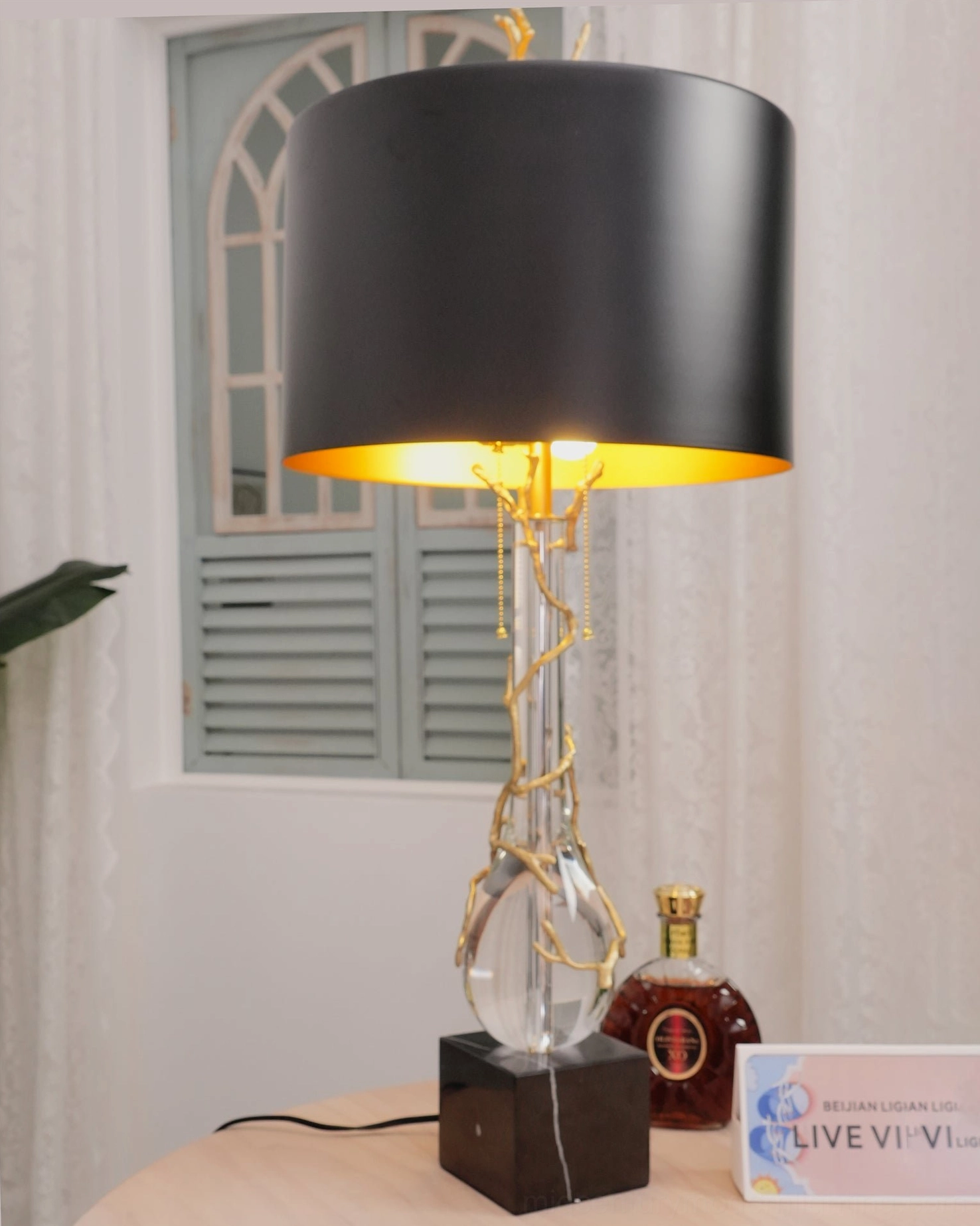 Lora modern table lamp low frontal perspective on tabletop with window backdrop and decorative styling