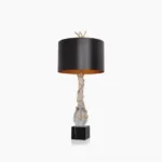 Lora table lamp front studio view with black drum shade, gold twig finial, brass accents, and black marble base on white background