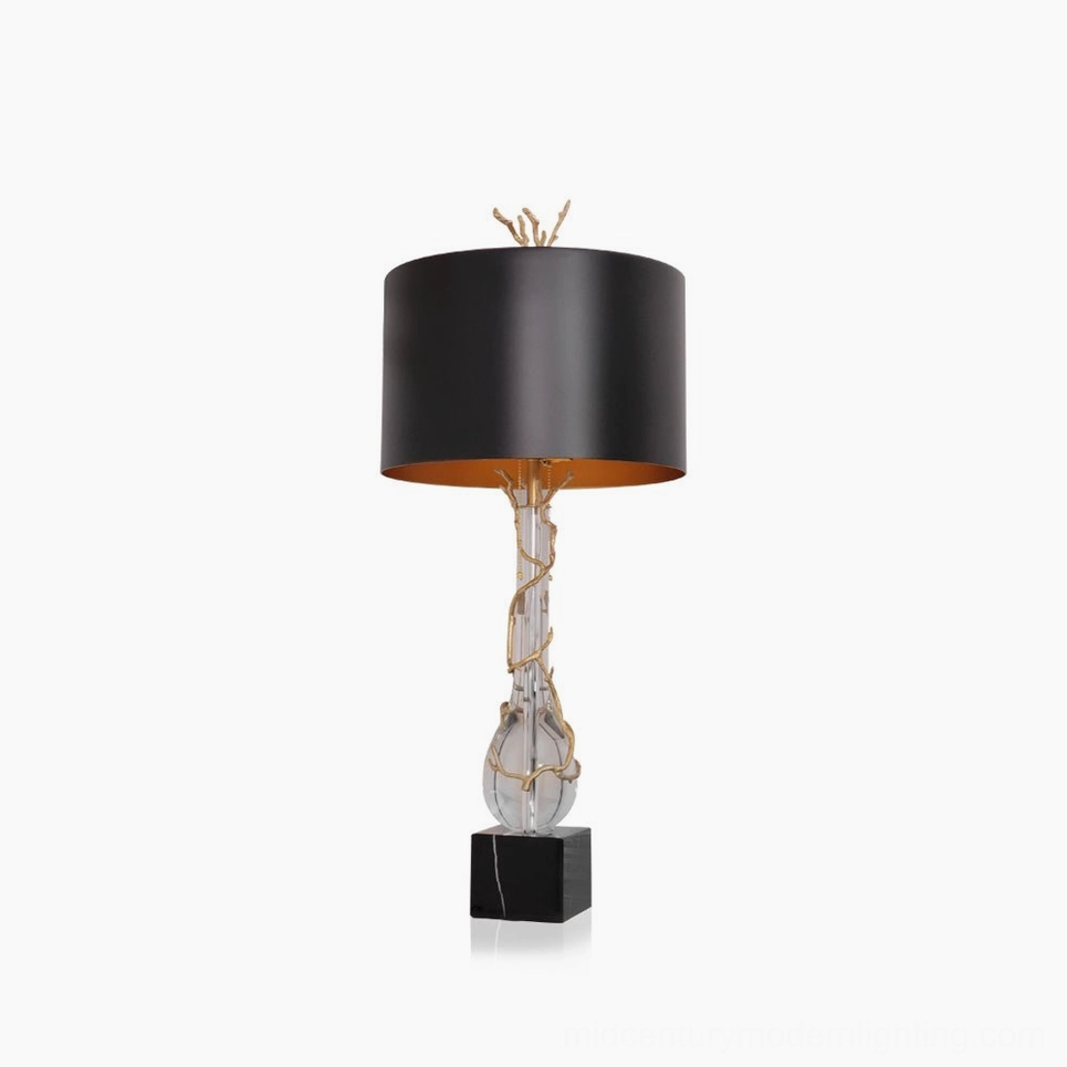 Lora table lamp front studio view with black drum shade, gold twig finial, brass accents, and black marble base on white background