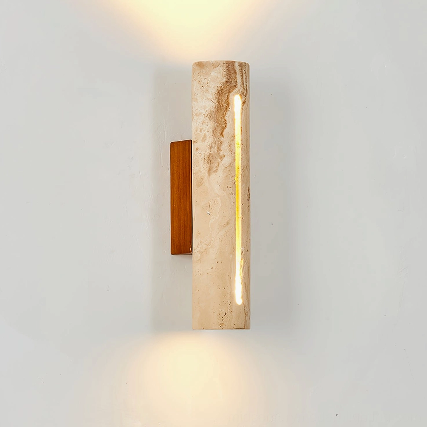 Lorelei travertine wall sconce lit on white interior wall, demonstrating warm ambient glow and natural stone veining pattern